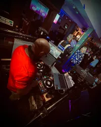 High-angle shot of a Jon focused on his mixing decks during a live set in a busy pub