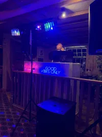 A photo of Jon standing behind the decks at an event with blue lighting